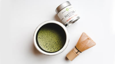cup of matcha tea with whisk and mizuba brand matcha container